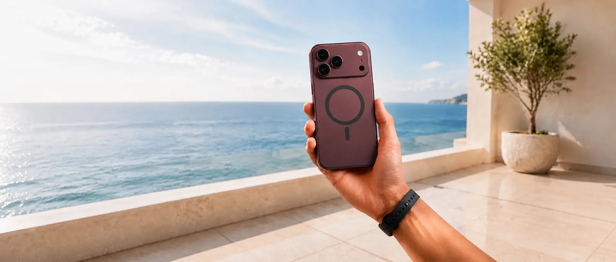Burgundy magnetic phone case with a black ring held on a sunny ocean terrace.
